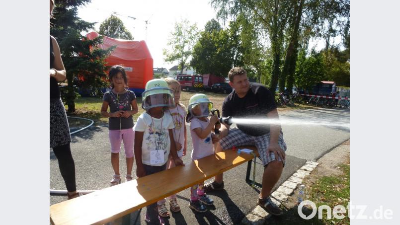 Die vierjährige Mia kann kaum den Feuerwehrschlauch greifen. Aber sie schafft es, das "Feuer" im Übungshäuschen zu löschen. Lena und Isabel schauen ihr zu. Bild: bk