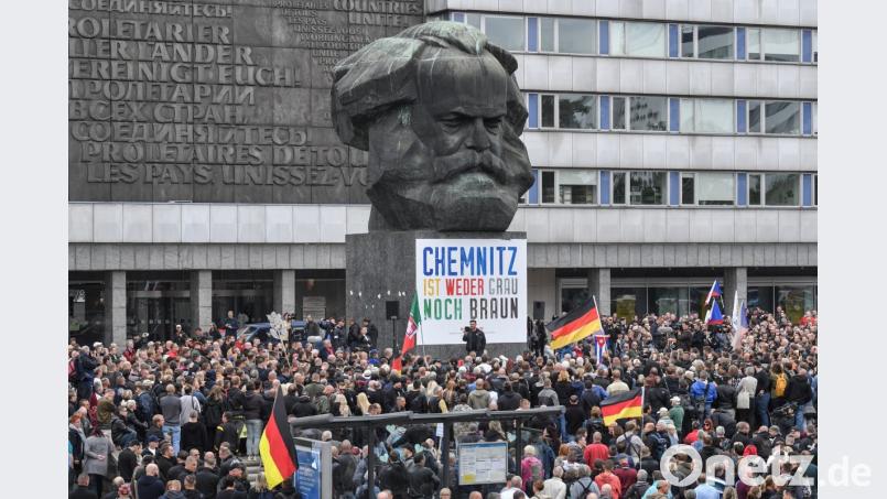 Teilnehmer der Kundgebung der rechtspopulistischen Bürgerbewegung Pro Chemnitz versammeln sich vor dem Karl-Marx-Denkmal, an dem immer noch ein Plakat des Bündnisses Chemnitz Nazifrei hängt. Bild: Boris Roessler