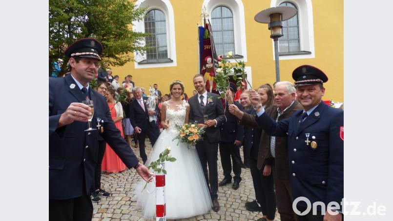 Das Brautpaar Heide Zitzmann und Patrick Fuchs beim Durchschreiten des Rosenspalier der Feuerwehr Lerau mit Vorsitzenden Peter Schwabl (links) und der Vereinsfahne Bild: sl