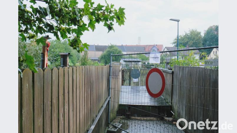 Der Grafenwöhrer „Kirchsteig“ unterhalb der Alten Pfarrkirche ist ab sofort gesperrt. Ein Metall-Bauzaun, aufgestellt vom städtischen Bauhof, versperrt den Zugang zur Fußgängerbrücke über den Thumbach. In der Bauausschusssitzung begründete Bürgermeister Edgar Knobloch die Schließung mit Sicherheitsbedenken. „Die Brücke ist einsturzgefährdet“, teilte er den überraschten Mitgliedern des Bauausschusses mit. Knobloch verwies auf eine Brückenkontrolle, bei der marode Eisenträger festgestellt worden seien. Knobloch berichtete gleichzeitig von Bemühungen des Stadtbauamtes, mit städtischen Materialien, etwa mit schweren Holzbohlen oder mit sicheren Eisenträgern, eine Behelfsbrücke zu erstellen. Stadtrat Josef Neubauer empfahl, diese angedachte Notlösung mittelfristig durch einen barrierefreien Neubau zu ersetzen. Gespräche mit dem Amt für Wasserwirtschaft sollen folgen. Bild: do