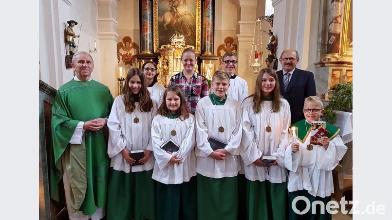 Pfarrer Josef Most (links) nimmt Max Mitlmeier (rechts) in der Schar der Ministranten auf. Bild: gi