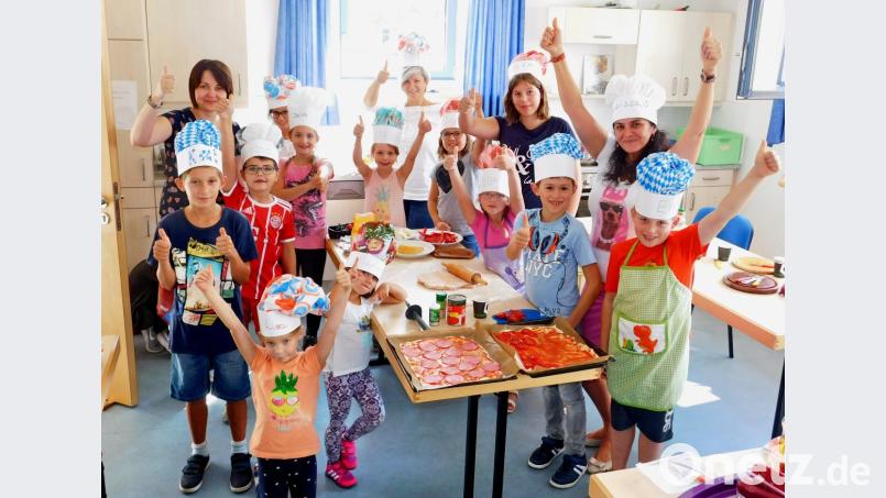 Jugendbetreuerin Larissa Maier (Zweite von rechts), Anna Burbach (hinten links) und Kathrin Richtmann (hinten Mitte) leiten die Mädchen und Buben bei der Zubereitung von Pizza und Pasta an. Bild: hai