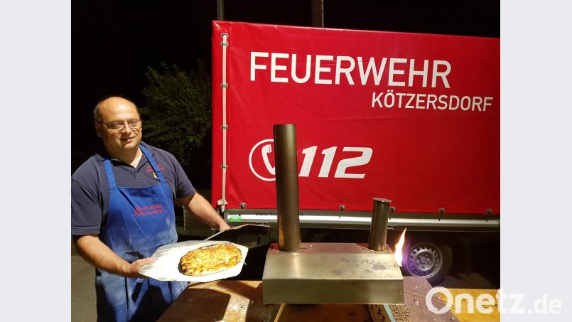 Der Kötzersdorfer Feuerwehrkommandant Markus Nickl stellt sich selbst vor einem kleinen Pizzabackofen. Rasch sind die belegten Fladen darin fertig gebacken. Bild: mde