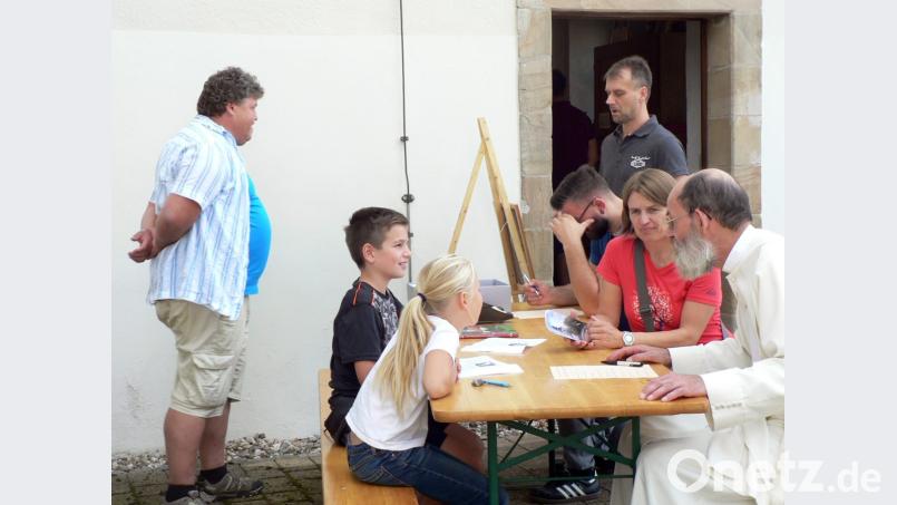 Zum „Tag des offenen Denkmals“ gibt es auch ein Kirchturm-Quiz. Hier wird nach der Höhe des Kirchturms, Anzahl der Stufen zum Glockenstuhl und nach dem Baustil gefragt. Pater Benedikt Schuster (rechts) hilft den Kindern. Bild: lep
