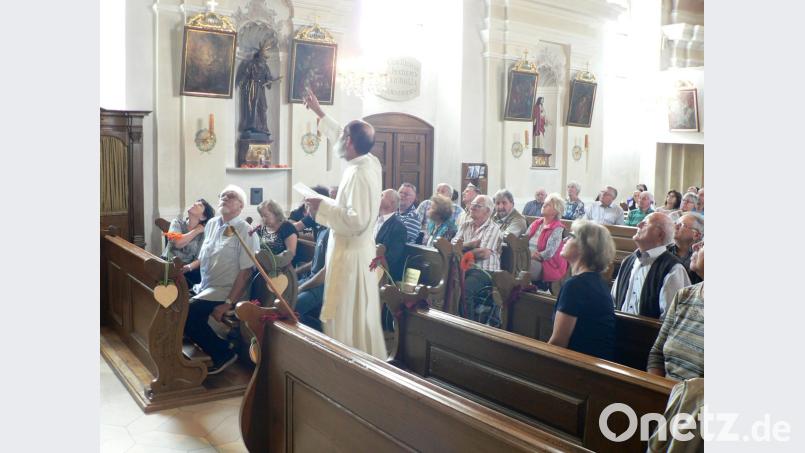 Pater Benedikt Schuster gibt einen kurzweiligen Streifzug durch die bewegte Geschichte der bemerkenswerten Rokokokirche in Oberbibrach. Bild: lep
