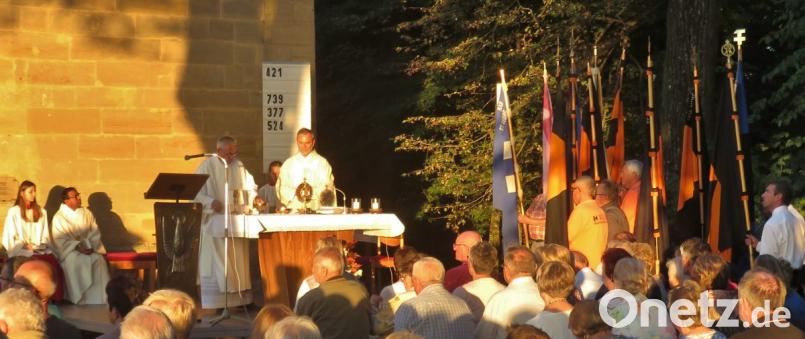 Die letzten Sonnenstrahlen des Tages tauchen Bergkirche und Vorplatz in warmes Licht. Pfarrer Josef Irlbacher (rechts) zelebriert mit Diakon Dieter Gerstacker und Pfarrvikar Hruday Kumar Madanu (links sitzend) die Eucharistie. Bild: rha