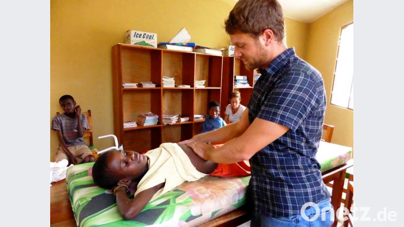 Internist Daniel Quandt untersucht einen Jungen. Als Behandlungsliege dient ein Schultisch. Bild: Hanna Gibbs