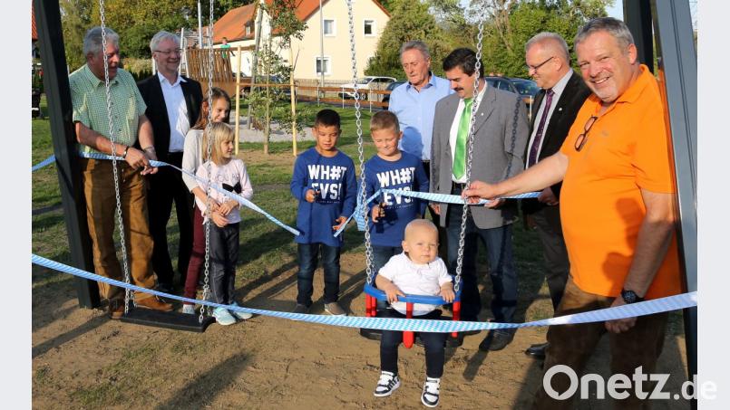 Jonas und Lukas Striegl durchschneiden das Einweihungsband für die neue Schaukel zerschneiden. Der kleine Leon machte schon mal eine Sitzprobe. Bild: mef