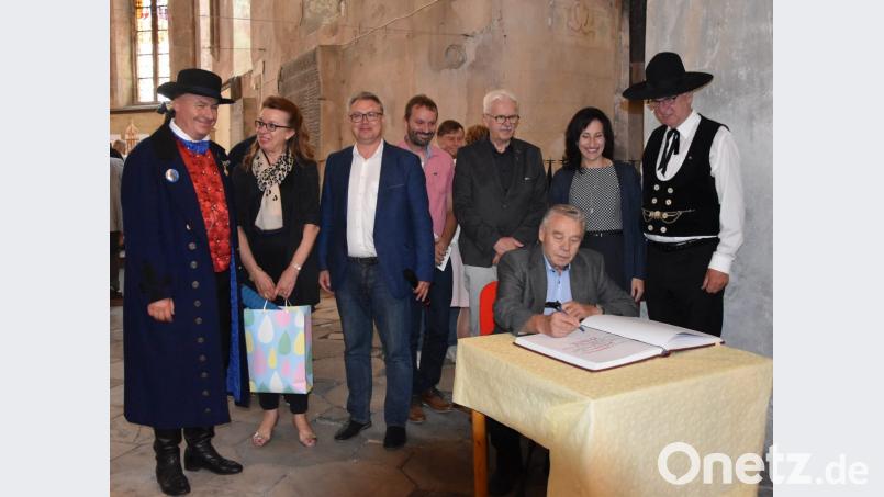 Josef Hauer trägt sich ins Stiftungsbuch ein. Über die Schulter schauen ihm (von links) der Übersetzer in Egerländer Tracht, Ulrika Hart, Bürgermeister Michal Pospísil, Konrad Dippel, Rainer Christoph, Bürgermeisterin Tanja Schiffmann und Karl Müller. Bild: cr