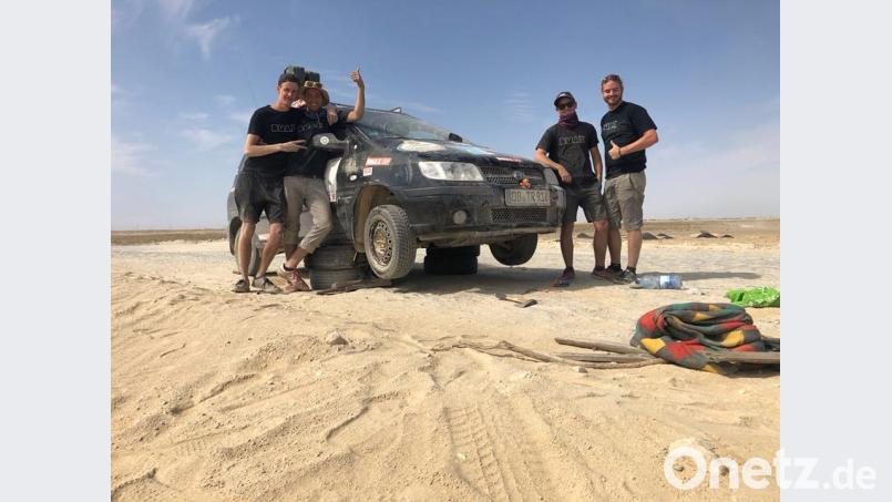 Fachmännisch aufgebockt ist anders: Beim Hyundai riss der Unterboden auf einer Sandpiste ab. Bei 40 Grad und ohne Schatten, während der Wüstensand ins Gesicht weht, haben die vier das Auto mit Lochband und Kabelbinder halbwegs repariert. Bild: exb