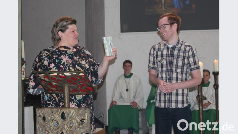 Gemeindereferentin Kathrin Blödt übergibt Roman Sanders ein Regensburger Gotteslob. Bild: wec