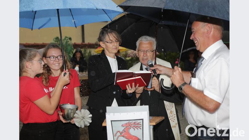 Trotz eines heftigen Gewittergusses lassen sich die Ministrantinnen (links) und Bürgermeister Roland Strehl (rechts) bei der Einweihung der neuen Theuerner Brücke den Spaß nicht verderben. Pfarrerin Birgit Schwalbe-Eberius und Ruhestandsgeistlicher Josef Beer übernehmen den kirchlichen Part. Bild: Wolfgang Steinbacher
