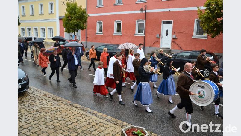 Die Teilnehmer des Kirchenzugs zum Patrozinium schützen sich mit Regenschirmen. Für die Musikanten der Blaskapelle ist dies nur bedingt möglich. Bild: fjo