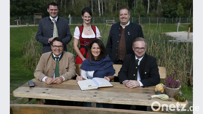 Landwirtschaftsministerin Michaela Kaniber (vorne, Mitte) trägt sich nach einem Rundgang im Erlebnispark „Wasser-Fisch Natur“ ins goldene Buch der Gemeinde Wackersdorf ein. Flankiert wird sie dabei von Landrat Thomas Ebeling, Bürgermeister Thomas Falter, Christina Bauer, Manfred Wendl und Landtagsabgeordnetem Alexander Flierl (alle CSU, von links). Bild: Hösamer