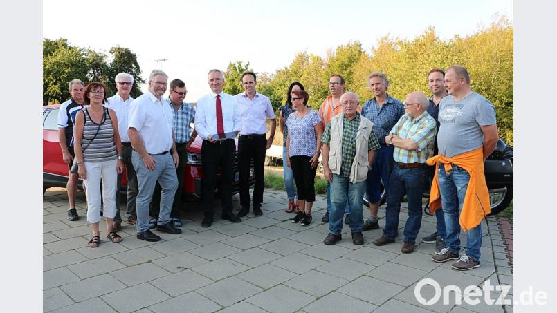 Landtagsabgeordneter Harald Schwartz und Bürgermeister Hans-Jürgen Strehl (Sechster und Siebter links) zeigen Edelsfelder Bürgern am Tablet den aktuellen Planungsstand für die Kreuzung B 85 und AS 6. Hinter der Baumreihe wird die neue Anbindung der AS 6 erfolgen. Bild: gru