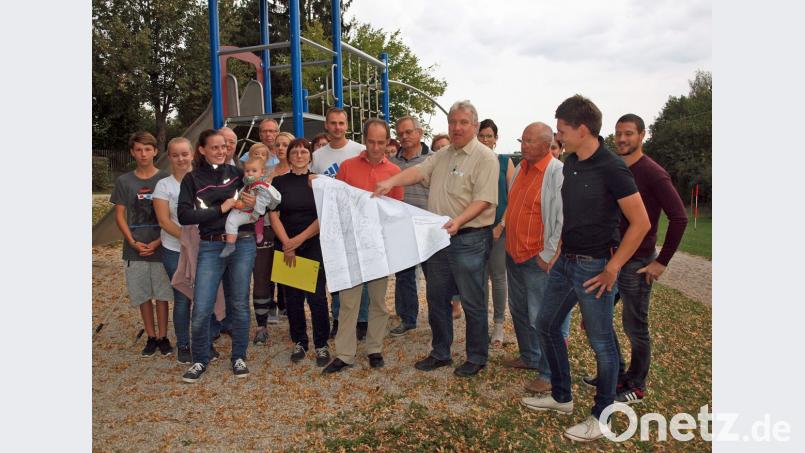 Zahlreiche Interessierte kommen zum Vor-Ort-Termin auf den bisherigen Spielplatz, wo Bürgermeister Markus Dollacker gemeinsam mit den Architekten Stephan und Martina Dietrich (ab Viertem von rechts) vom Planungsbüro Stadt und Raum Amberg den Bebauungsplan mit Verlegung des Spielplatzes vorstellten. Bild: sön