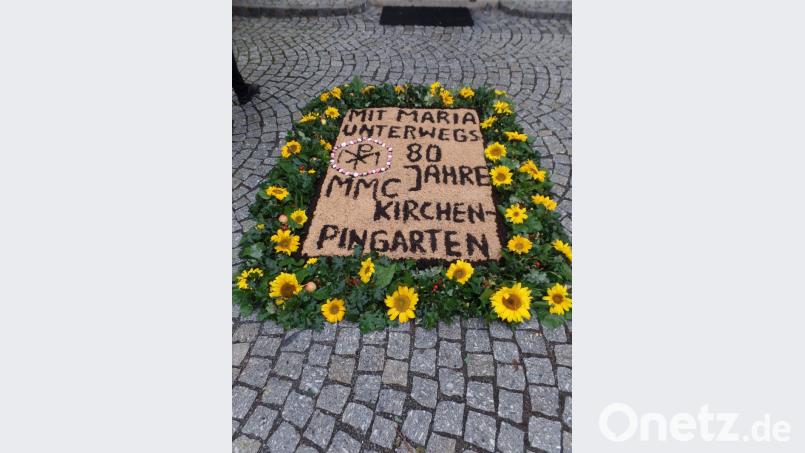 „Mit Maria unterwegs, 80 Jahre MMC Kirchenpingarten“ steht auf dem mit Sonnenblumen eingerahmten Blumenteppich am Eingang zum Gotteshaus. Bild: Brendel, Hubert (BR)