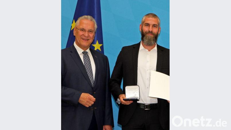 Minister Joachim Herrmann überreicht Simon Wissing Medaille und Urkunde. Bild: exb