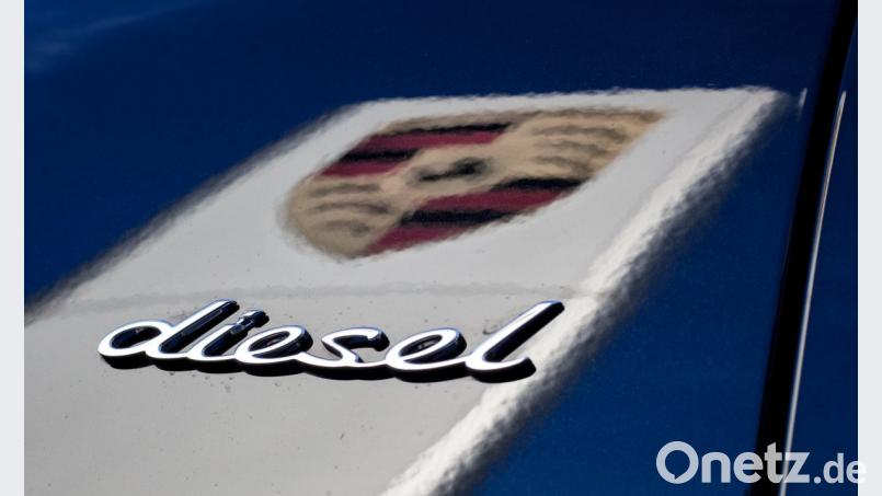 Das Logo des Fahrzeugherstellers Porsche in der dunklen Lackierung eines Porsche Cayenne, während dabei der Schriftzug &quot;Diesel&quot; auf dem Wagen zu sehen ist. Bild: Christoph Schmidt/dpa
