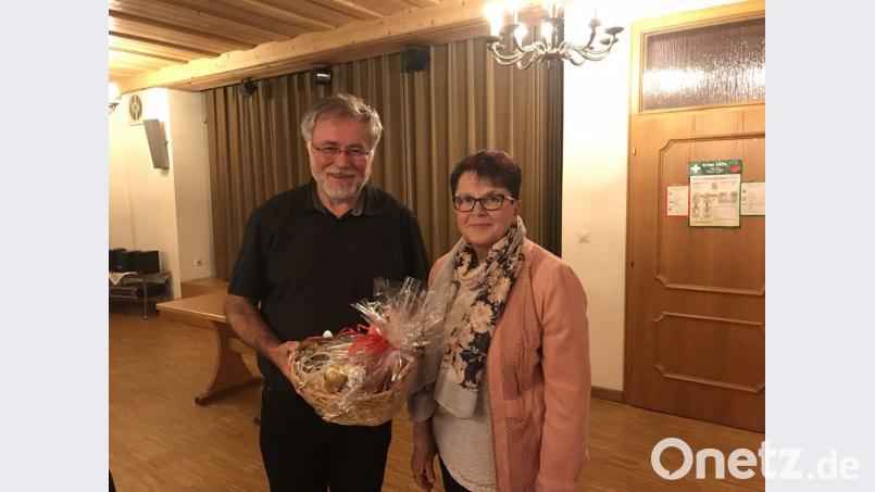 Zum Dank für seine Ausführungen überreicht Marita Kuchenreuther, an Pfarrer Edmund Prechtl einen Brotzeitkorb. Bild: soj