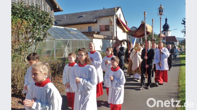 Herrliches Spätsommerwetter begleitet die eucharistische Prozession durch die Dorfstraßen. Unter dem Baldachin trägt Pfarrvikar Augustin Oburota die Monstranz. Im Hintergrund (rechts) der Kirchturm der „Sankt Michaelskirche“. Bild: Brendel, Hubert (BR)