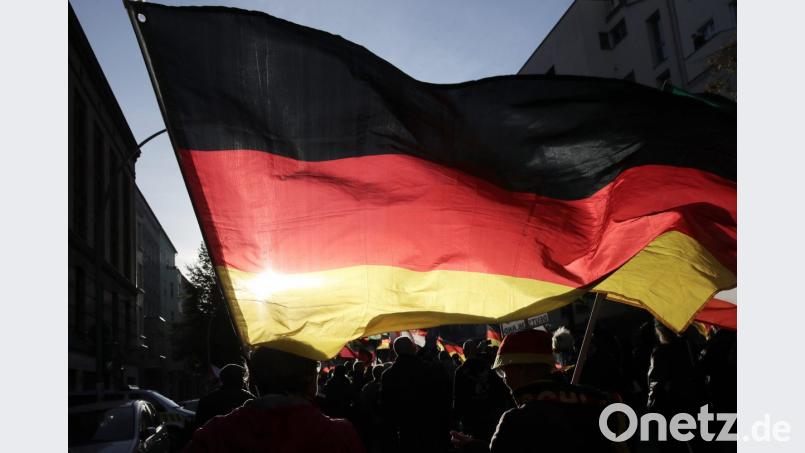 Teilnehmer der rechtspopulistischen Demonstration "Tag der Nation" des Bündnisses "Wir für Deutschland" ziehen mit einer Deutschlandfahne am Tag der deutschen Einheit durch Berlin. Bild: Michael Kappeler/dpa
