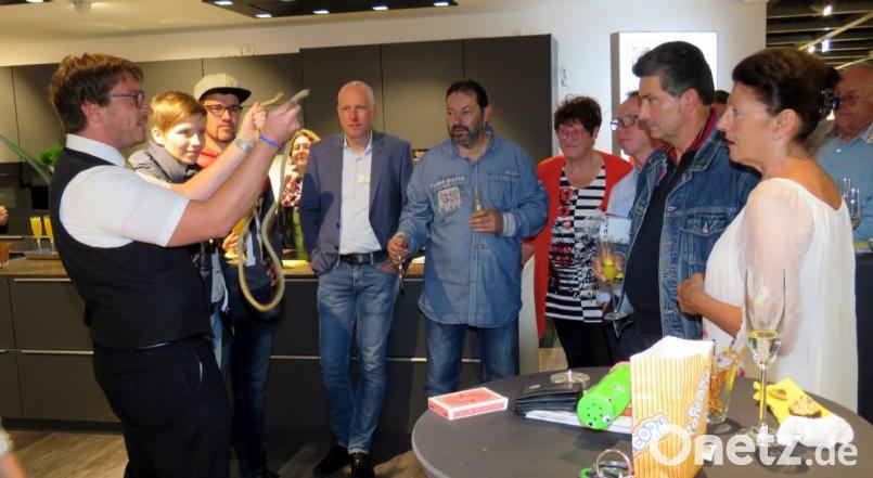 Zauberer Marco Knott (links) verzauberte nicht nur die Gäste der Neueröffnung. Auch Firmeninhaber Jörg Kulzer (Sechster von rechts), Seniorenchefin Lieselotte Kulzer (Vierter von rechts) und Prokurist Wolfgang Horn (Dritter von rechts) nahmen sich kurz Zeit für die Trickkiste des Bärnauers. Bild: ubb