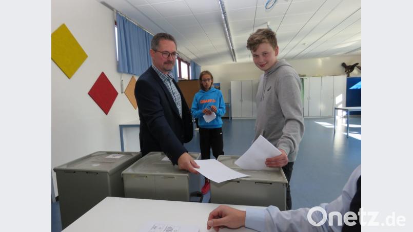Schulleiter Stephan Drexler zeigt dem Schüler Andreas Weiß (v. li.), inwelche Urne er seinen ausgefüllten Wahlzettel werfen soll. Bild: ubb