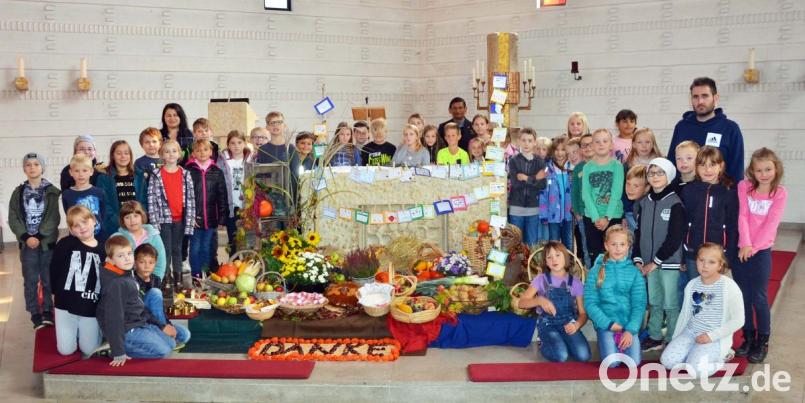 Stolz auf ihr Werk: Die Buben und Mädchen der Grundschulklassen 3 und 3/4 übernehmen heuer das Schmücken des Altars in der Pfarrkirche zum Erntedankfest. Bild: ü