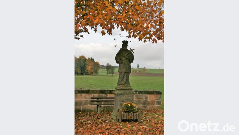 Inmitten prächtigem Herbstlaub steht die Statue des Heiligen Nepomuk in Speinshart. Bild: Rainer Christoph