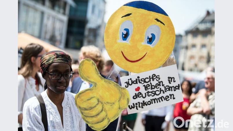 Eine junge Frau trägt auf dem Marktplatz in Bonn ein Schild mit der Aufschrift "Jüdisches Leben in Deutschland willkommen".. Mehrere hundert Menschen demonstrieren an diesem Tag gegen Antisemitismus. Bild: Federico Gambarini/dpa