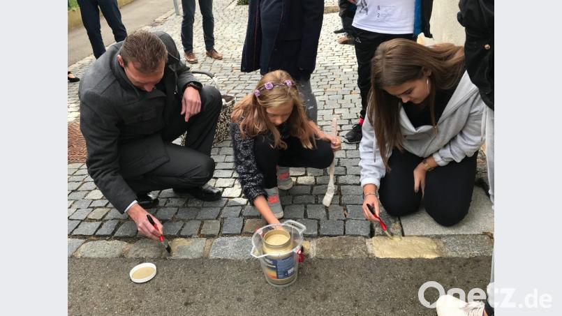 Gold für Pflastersteine: Da kann selbst Bürgermeister Ernst Schicketanz nicht widerstehen und greift zum Pinsel. Bild: cr