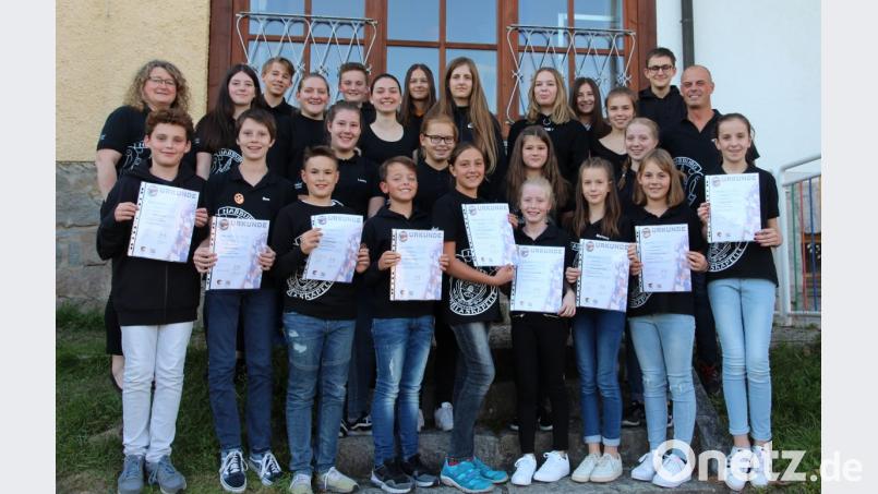 Freudestrahlend präsentieren die ausgezeichneten Jungbläser ihre Urkunden im Kreis ihrer Orchesterkollegen zusammen mit den musikalischen Leiter Markus Ferstl (Zweiter von rechts) und der Leiterin des Nachwuchsorchesters Karin Raab (links). Bild: bph