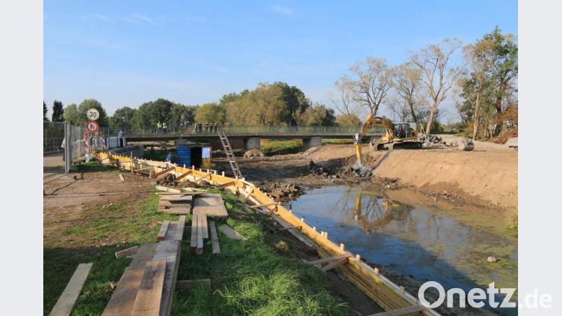 Die alte Wehranlage wurde teilweise abgebrochen und wird nun abgetragen. Hier soll schon bald eine neue Rampe entstehen. Auf der Brücke inspiziert der Bauausschuss die Baustelle. Bild: sne