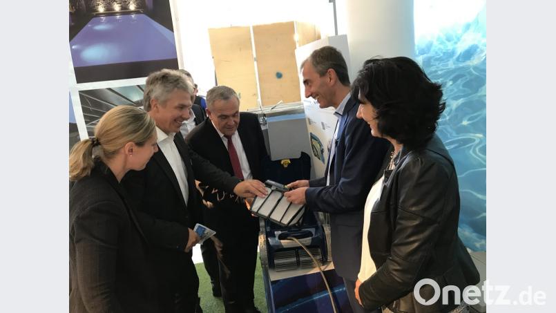 Den Pool reinigt heute ein Roboter; Oberbürgermeister Kurt Seggewiß (Mitte), Messeleiter Gunnar von Grawert-May und Verlegerin Viola Vogelsang-Reichl (links) lassen sich von Reinhard und Gabi Mathy (aquavariapools, rechts) den Roboter erklären. Bild: eig