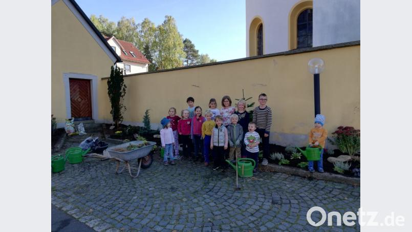 Die Grashüpfer der Steiner Kirchengemeinschaft und die Gartenzwerge des OGV Liebenstein bepflanzen das Blumenbeet vor der St.-Laurentius-Kirche in Stein. Bild: hä
