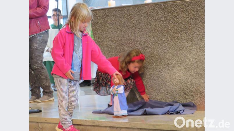 Mit Puppen und einem blauen Tuch stellen die Kindersymbolisch die Suche Jesu nach Aposteln dar. Bild: adj