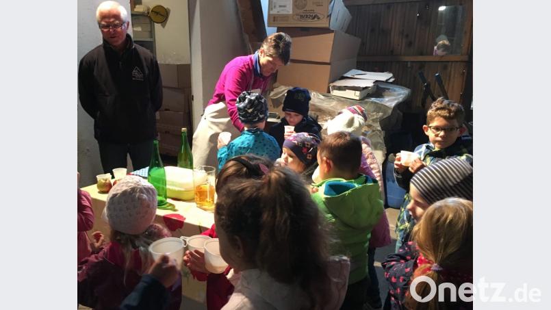 Roland Maier (links), der Vorsitzende des Obst- und Gartenbauvereins, erklärt den Mädchen und Jungen den Vorgang der Saftherstellung vom Anliefern der Äpfel bis zu deren Pressen. Begeistert sind die Kinder vom Geschmack des noch warmen Apfelsaftes, den ihnen Irmgard Sellmeyer (rechts) serviert. Bild: u