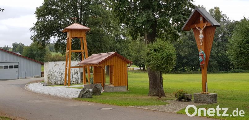 Dorfkreuz, Bushäuschen und Glockenturm bilden ein Ensemble in der Dorfmitte von Unterlind. Allerdings ist der Glockenturmbau noch nicht von allen akzeptiert. Bild: dob