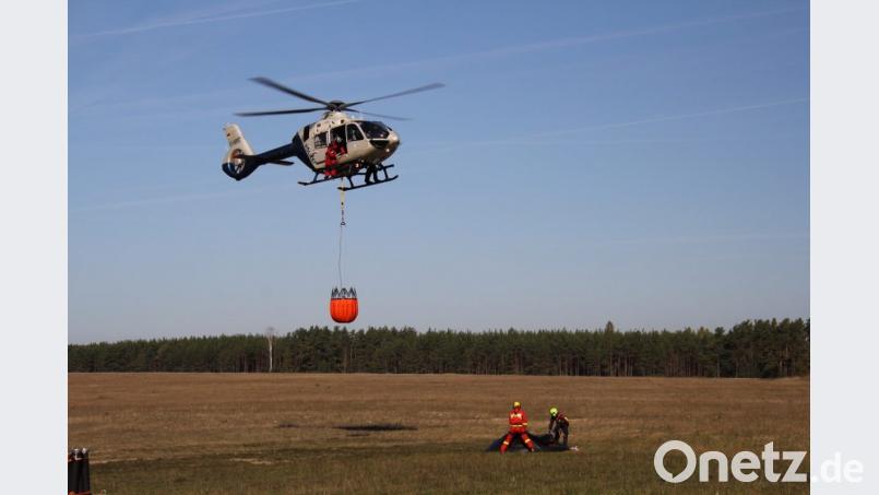 Ein Hubschrauber hebt mit einem Löschbehälter ab. Bild: xri