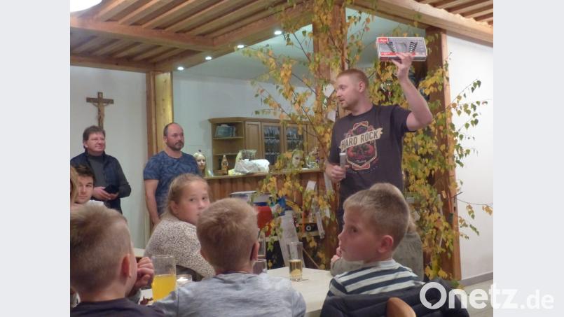 Der professionelle Auktionator „Hias“ bei seiner schweißtreibenden Aufgabe. Vorsitzender Bernhard Kammerer (Zweiter von links) reichte ihm die Gegenstände, Kassier Johann Balk sammelt das Geld ein. Bild: sl