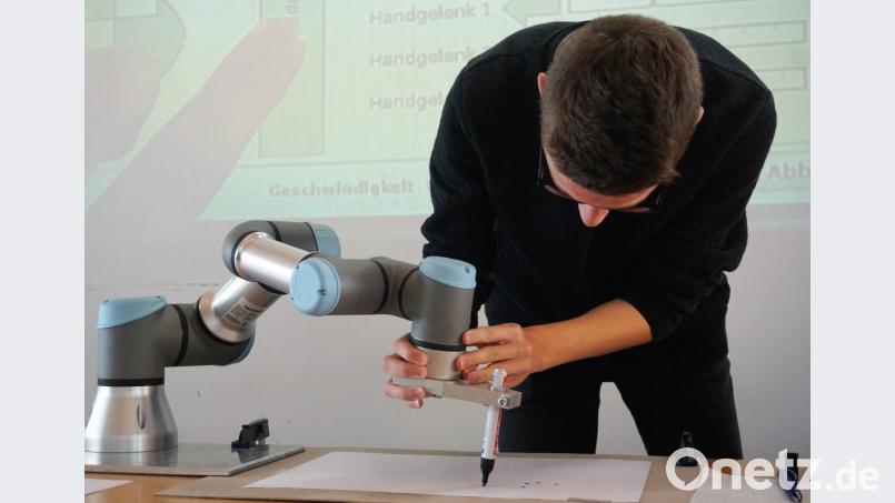 Ein Schüler positioniert „Fridolin“, den Tischroboter. Bild: exb