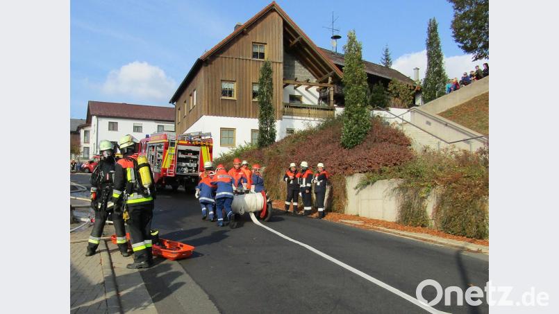 Atemschutzträger (links am Löschfahrzeug) und Jugendfeuerwehr (Bildmitte) im Einsatz beim Ziehen des aufgerollten Schlauches für eine 700 Meter lange Löschwasserleitung zum nahegelegenen Goldbrunnbach. Bild: sck