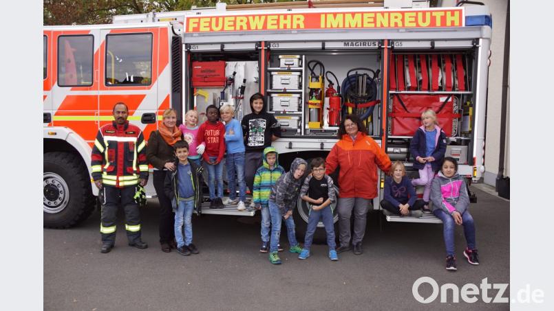 Claudia Schleicher (Vierte von rechts)) und Nadine Manhart (Zweite von links) besuchen mit der Offenen Ganztagsschule die Feuerwehr. Zweiter Kommandant Christopher Hörl (links) zeigt seinen jungen Gäste auch das Löschfahrzeug. Bild: bkr