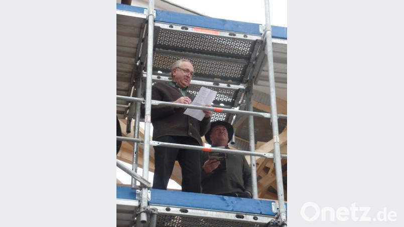 Holzingenieur Konrad Zimmermann vom gleichnamigen Zimmereibetrieb trägt den Richtspruch vor. Zum Gelingen der Maßnahme hebt er drei Mal das Glas und lässt es dann zerspringen. Bild: Brendel, Hubert (BR)