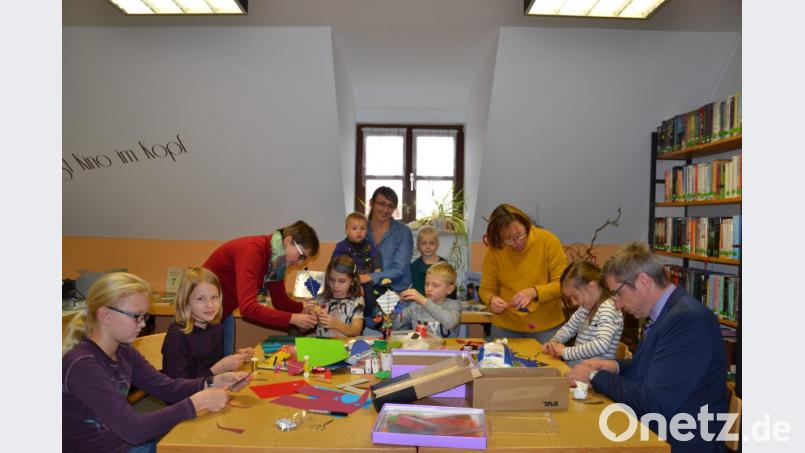 Mädchen und Buben basteln beim Büchereitag unter der Leitung von Gabriele Hierold und Claudia Rieß (von links). Auch Büchermeister Hermann Ach schnappt sich Schere und Kleber. Bild: gi