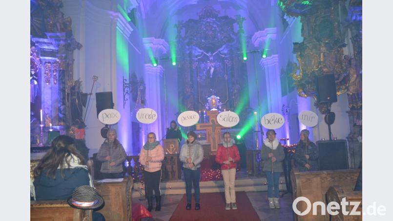 Die Lichtershow taucht die Wieskirche in bunte Farben. Die jüngeren Ministranten zeigen Schilder auf denen Friede in verschiedenen Sprachen steht. Überall soll es Frieden geben, denn ohne Frieden ist alles nichts. Bild: gi