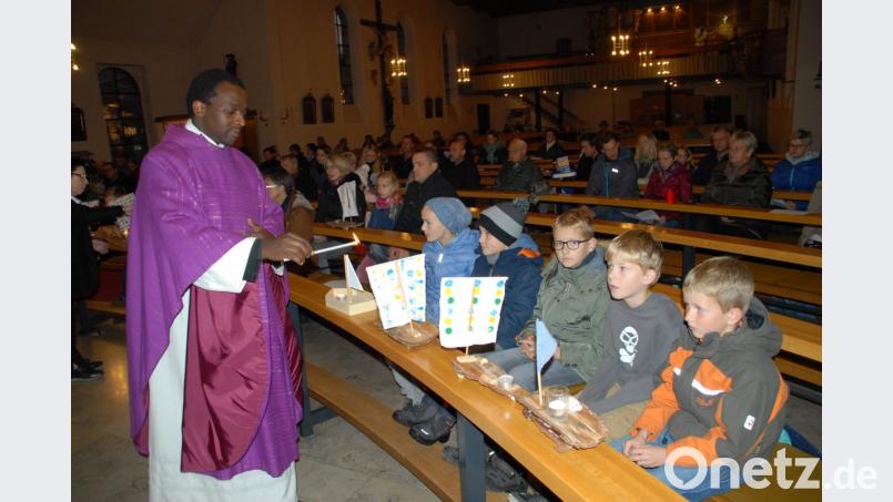 Pfarrer Joseph Uwitonze gibt das Feuer und das Licht der Osterkerze an die Kinder weiter und entzündet die Kerzen auf den Schiffchen. Bild: pop
