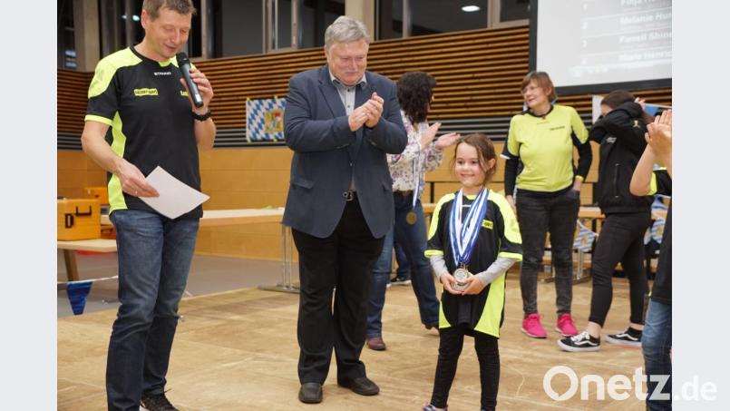 Die jüngste Teilnehmerin Tamina Bayer mit vielen Medaillen. Bürgermeister Manfred Porsch und Trainer Lothar Ziegler gratulieren. Bild: bkr