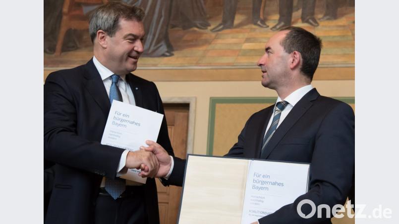 Ministerpräsident Markus Söder (links, CSU) und der Landesvorsitzende der Freien Wähler Hubert Aiwanger reichen sich nach der Unterzeichnung des neuen Koalitionsvertrags die Hand. Bild: Sven Hoppe/dpa